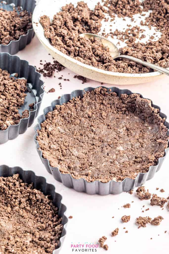 pressing crushed cookies into a tart shell