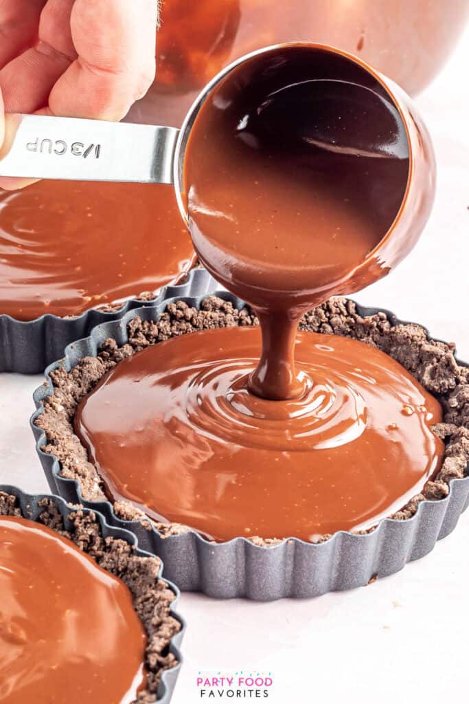 pouring a dairy free chocolate ganache into a cookie crust tart