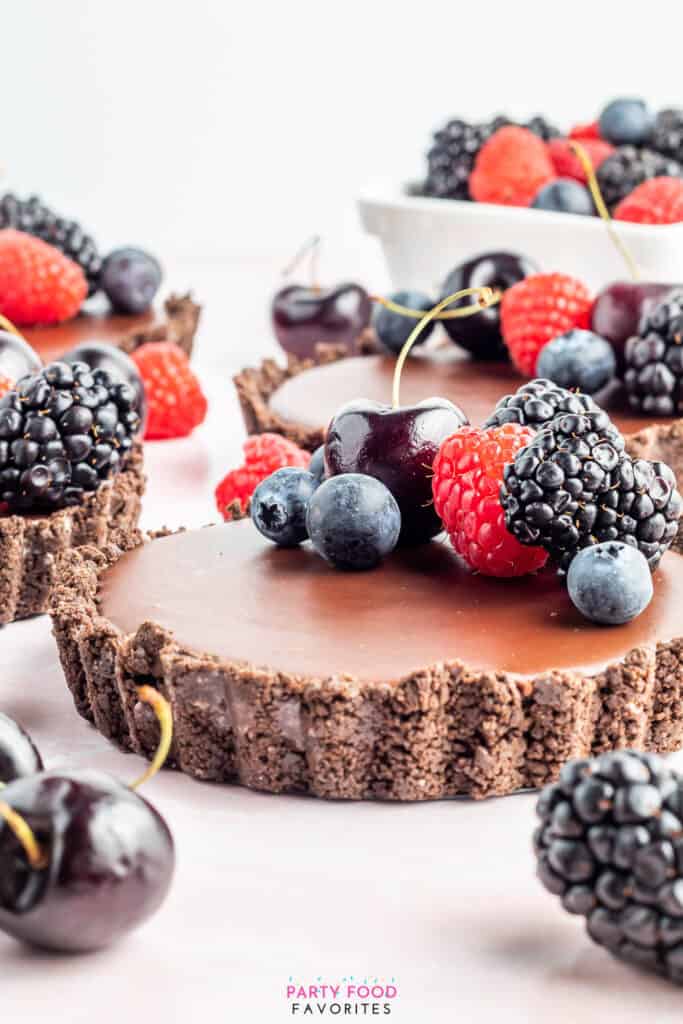 side view of berries and cherries on top of a double chocolate mini pie