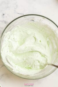 mixing cool whip with pistachio pudding mix