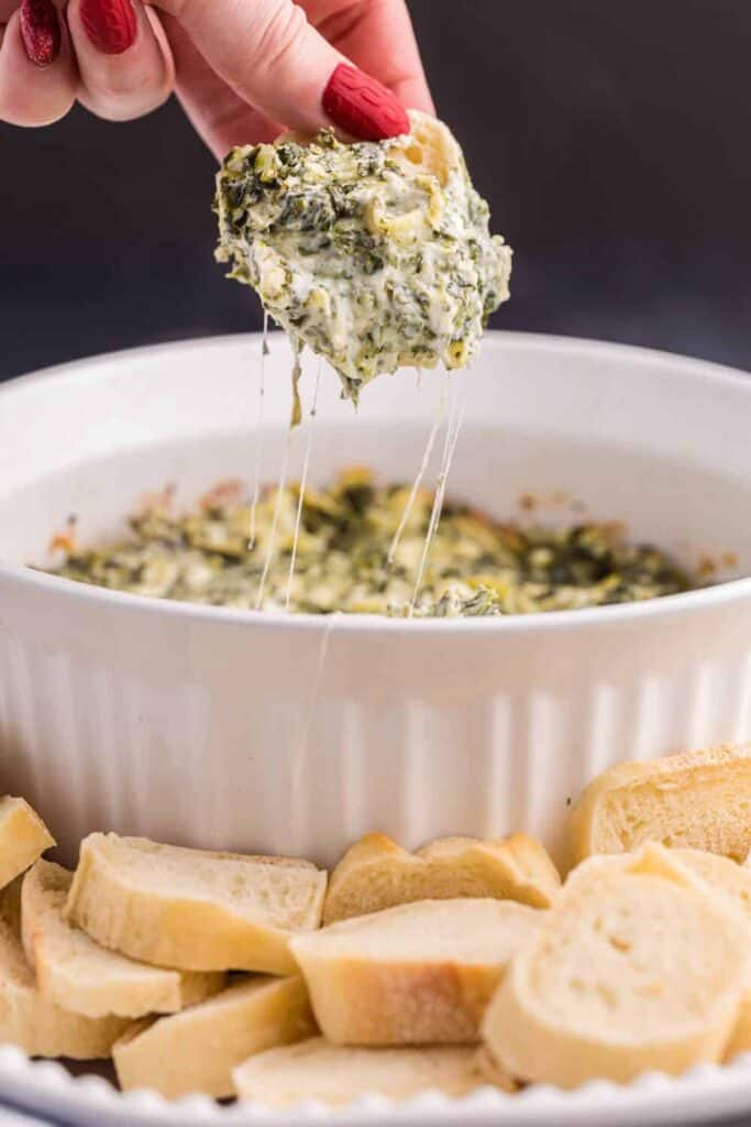 sliced baguette dipped into a low carb spinach artichoke dip