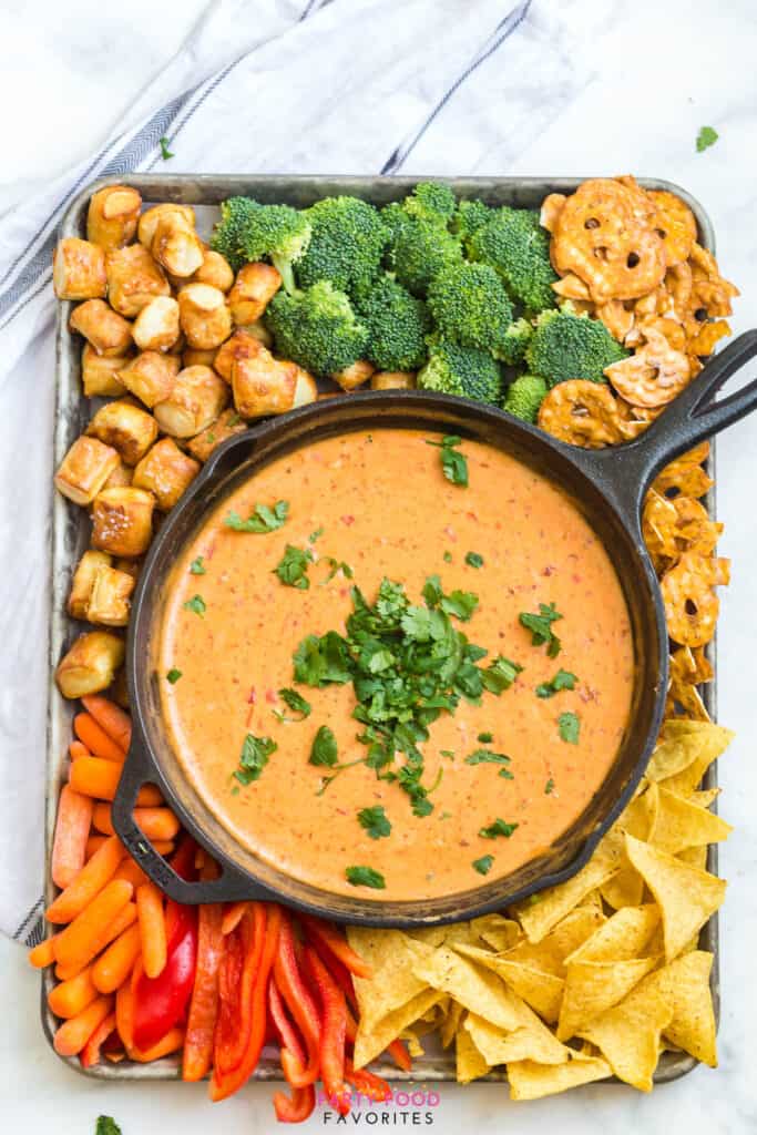 easy beer cheese dip in a cast iron skillet surrounded by chips and vegetables