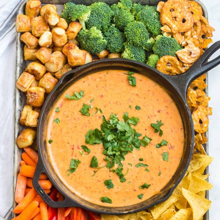 easy beer cheese dip in a cast iron skillet surrounded by chips and vegetables