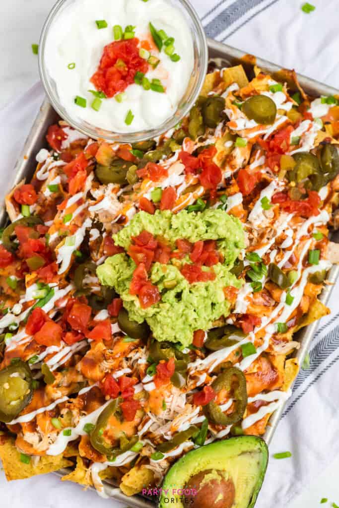 loaded nachos on a cookie sheet with sour cream and rotel