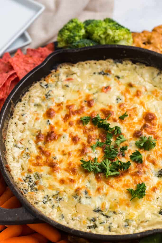 close up of a creamy baked spinach dip in a cast iron skillet
