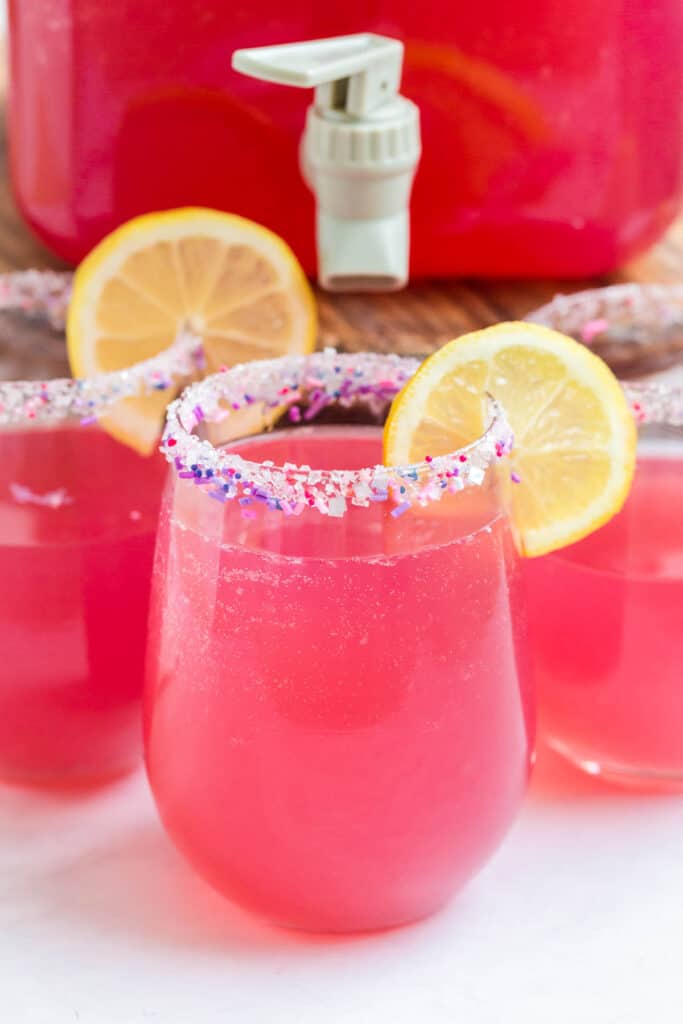 pink party punch with sliced lemon and sprinkles on a rim.