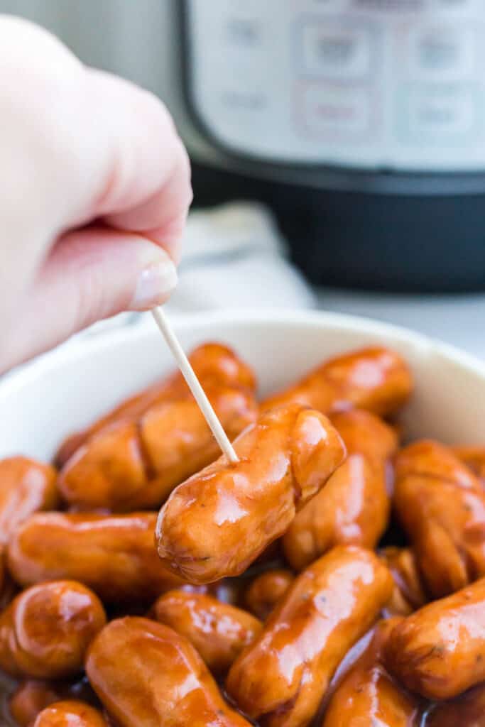 A toothpick lifting a little smokie covered in low carb, keto bbq sauce