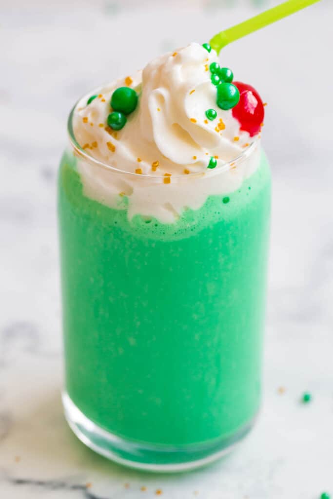 green vanilla mint milkshake close up with whipped cream, sprinkles, and maraschino cherries