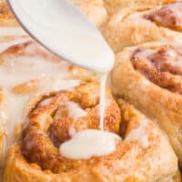 spooning frosting over cinnamon buns